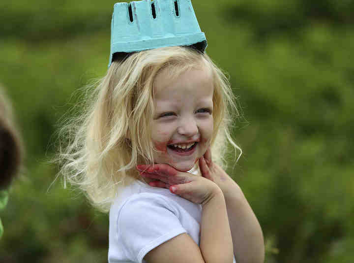 The hands and face of Florence Borders, 4, of Bexley, show colorful signs of strawberry picking and eating while she playfully puts her empty quart container on her head while visiting Doran's Farm Market in New Albany.  (Jonathan Quilter / The Columbus Dispatch)